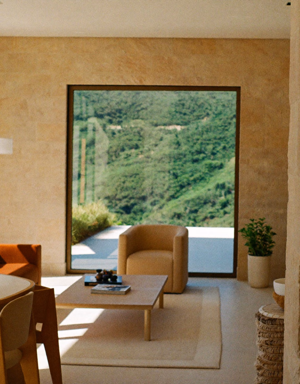 Bright interior with warm stone walls and tall windows onto green hills.