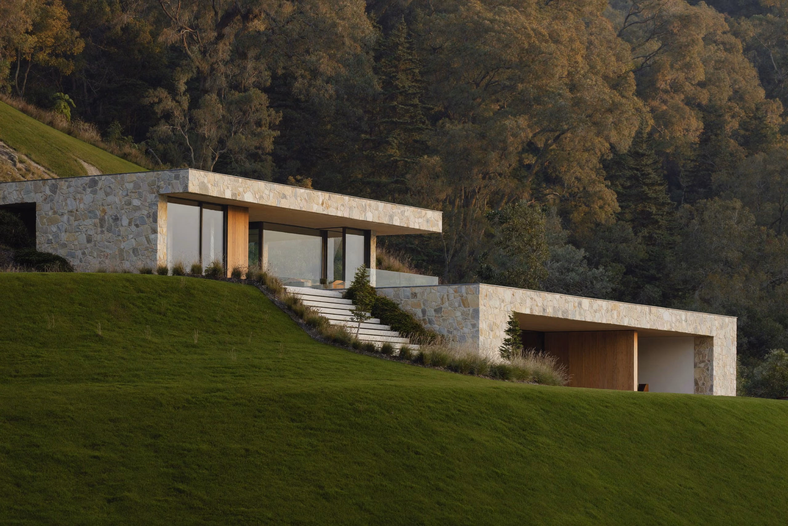 Modern limestone house on a green hillside in soft morning light.