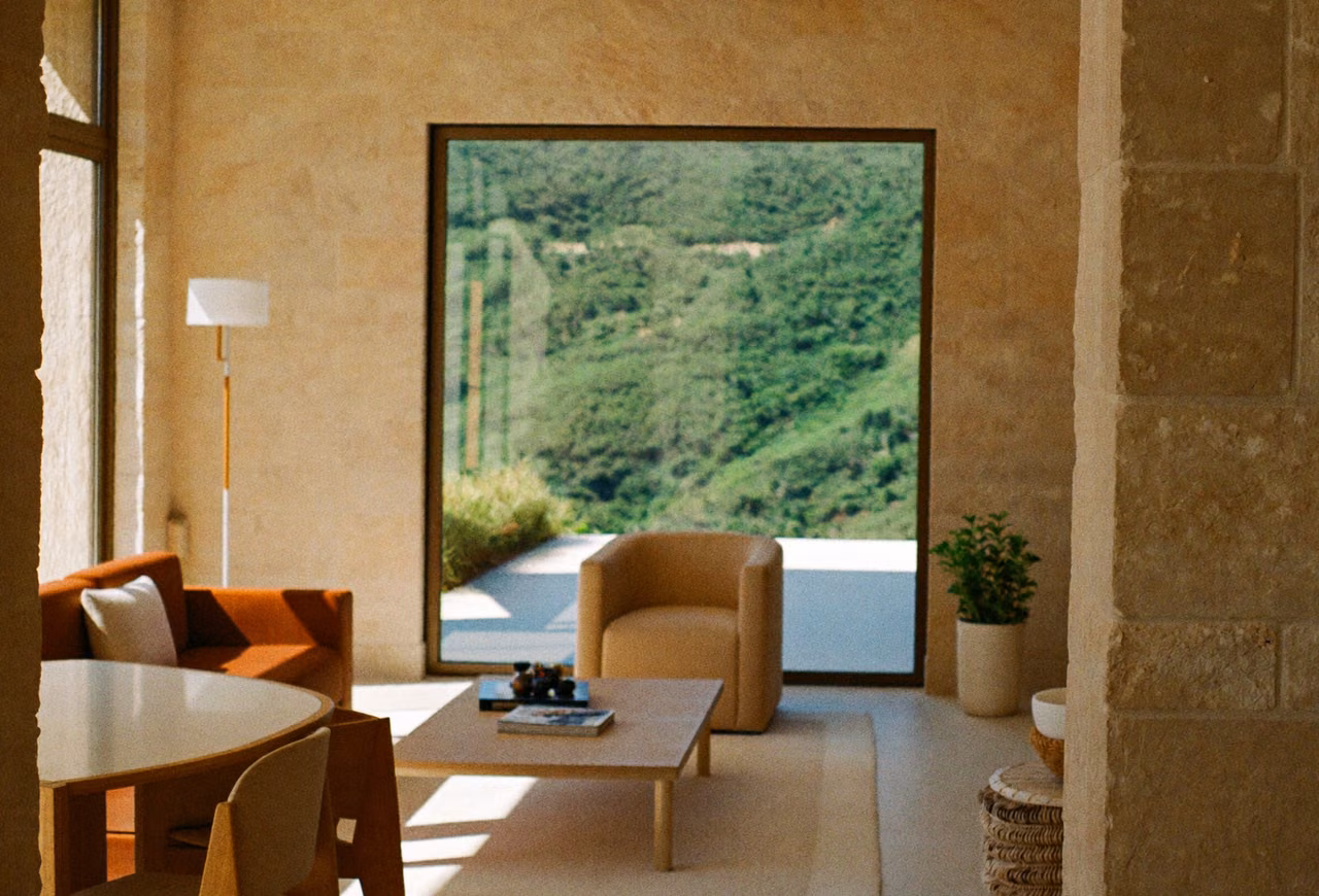 Bright interior with warm stone walls and windows looking onto green hills.